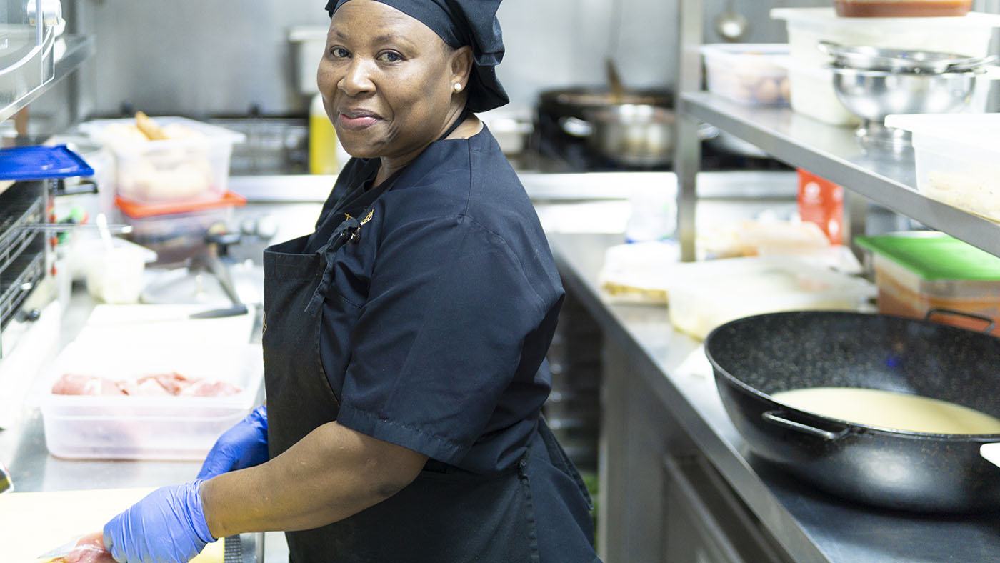 Photo of foodservice workers with proper hair cover, apron, and gloves